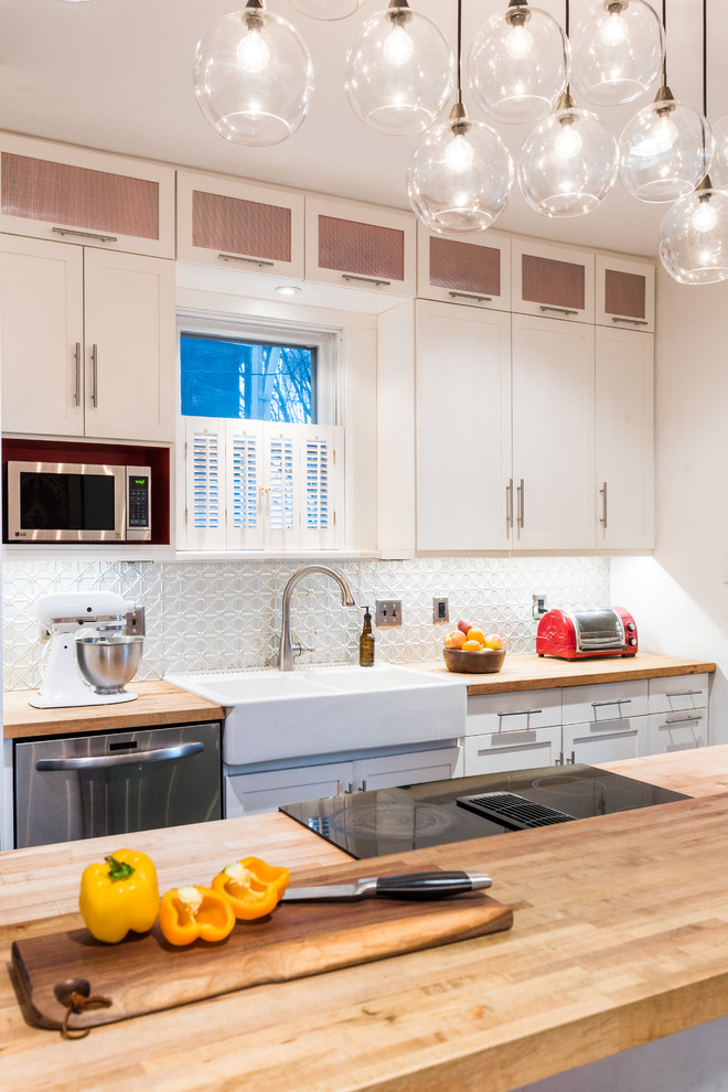 Example of a small galley dark wood floor and black floor enclosed kitchen design in DC Metro with a farmhouse sink, shaker cabinets, white cabinets, wood countertops, metallic backsplash, metal backsplash, stainless steel appliances, an island and multicolored countertops
