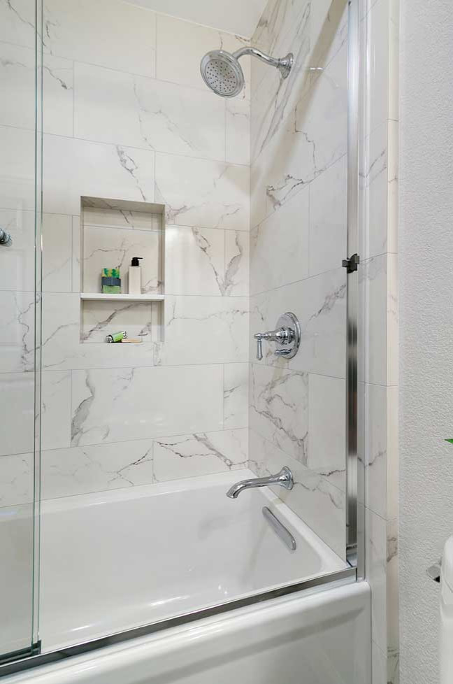 Design ideas for a small transitional bathroom in San Francisco with recessed-panel cabinets, blue cabinets, an alcove tub, a shower/bathtub combo, a two-piece toilet, white tile, porcelain tile, beige walls, porcelain floors, an integrated sink, grey floor, a sliding shower screen, white benchtops and a single vanity.