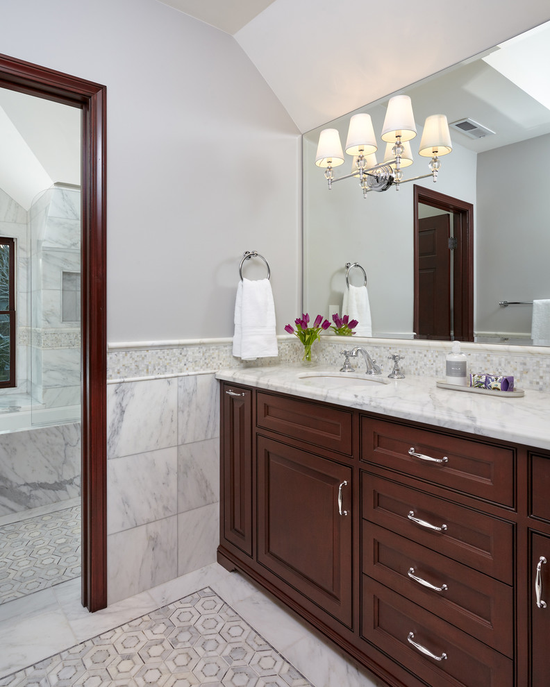 Photo of a mid-sized traditional master bathroom in San Francisco with marble, grey walls, marble floors, an undermount sink, marble benchtops, beaded inset cabinets, dark wood cabinets, a two-piece toilet, white tile, a drop-in tub, a shower/bathtub combo, grey floor, a hinged shower door and white benchtops.