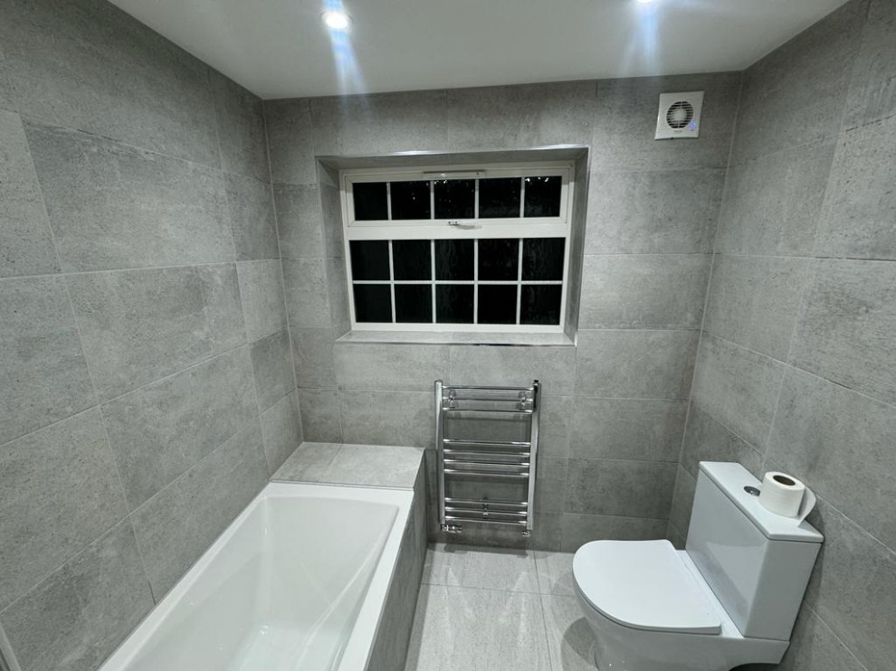 Exemple d'une petite douche en alcôve grise et blanche tendance avec un placard à porte shaker, des portes de placard blanches, une baignoire en alcôve, WC à poser, un carrelage gris, des carreaux de céramique, un mur gris, un sol en carrelage de céramique, un lavabo suspendu, un plan de toilette en granite, un sol gris, une cabine de douche à porte coulissante, un plan de toilette blanc, meuble simple vasque, meuble-lavabo suspendu et un plafond à caissons.