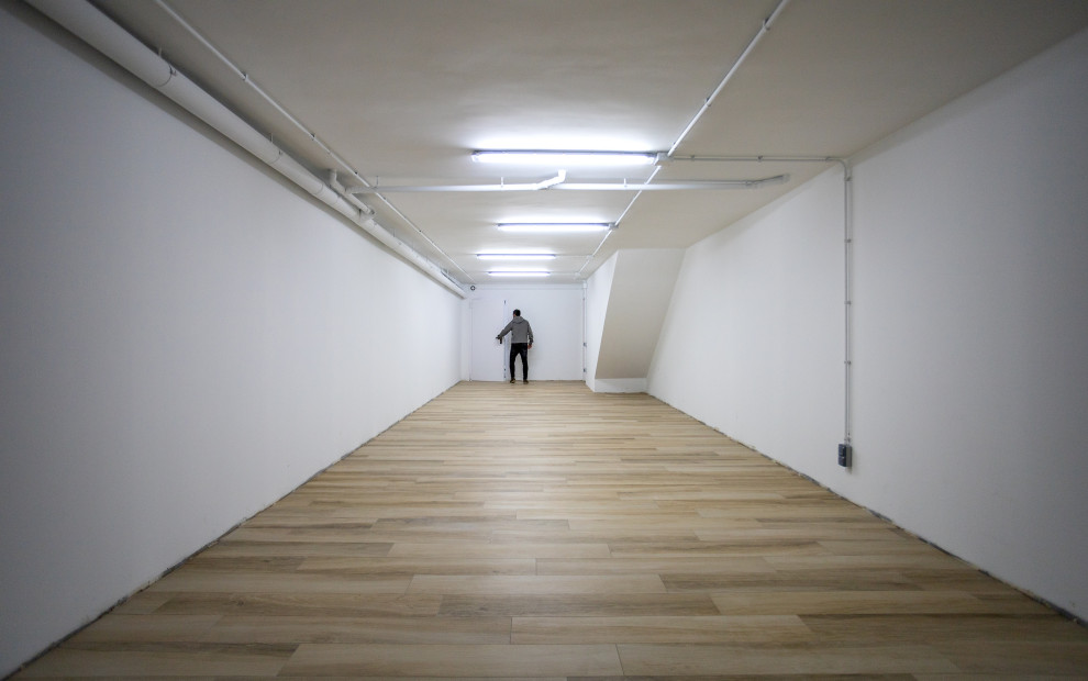 Großes Modernes Untergeschoss mit weißer Wandfarbe, braunem Holzboden, braunem Boden, eingelassener Decke und Tapetenwänden in Barcelona