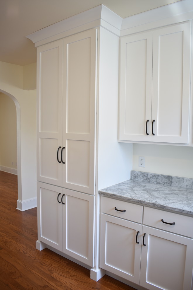 Example of a mid-sized transitional u-shaped medium tone wood floor and brown floor home design design with an undermount sink, recessed-panel cabinets, white cabinets, marble countertops, stainless steel appliances, no island and multicolored countertops