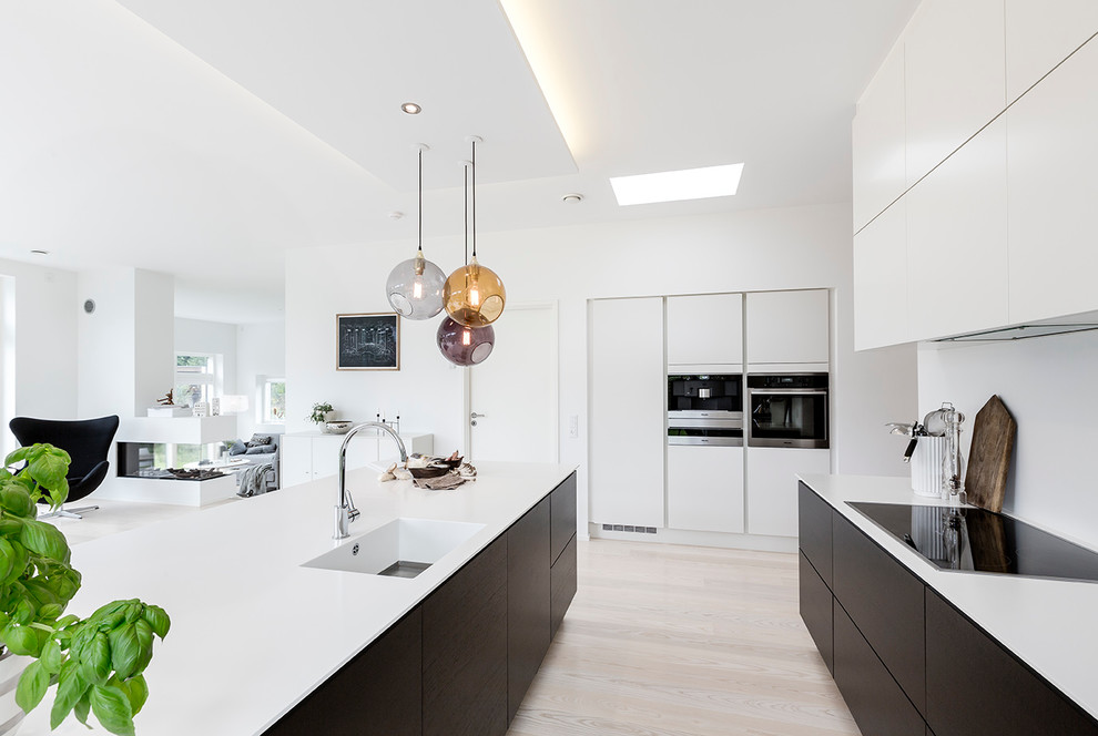 This is an example of a mid-sized modern open plan kitchen in Aarhus with flat-panel cabinets, quartzite benchtops, white splashback, panelled appliances, with island and beige floor.