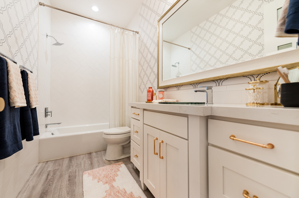 This is an example of a mid-sized transitional kids bathroom in Salt Lake City with shaker cabinets, white cabinets, a drop-in tub, a shower/bathtub combo, a two-piece toilet, white tile, ceramic tile, white walls and engineered quartz benchtops.