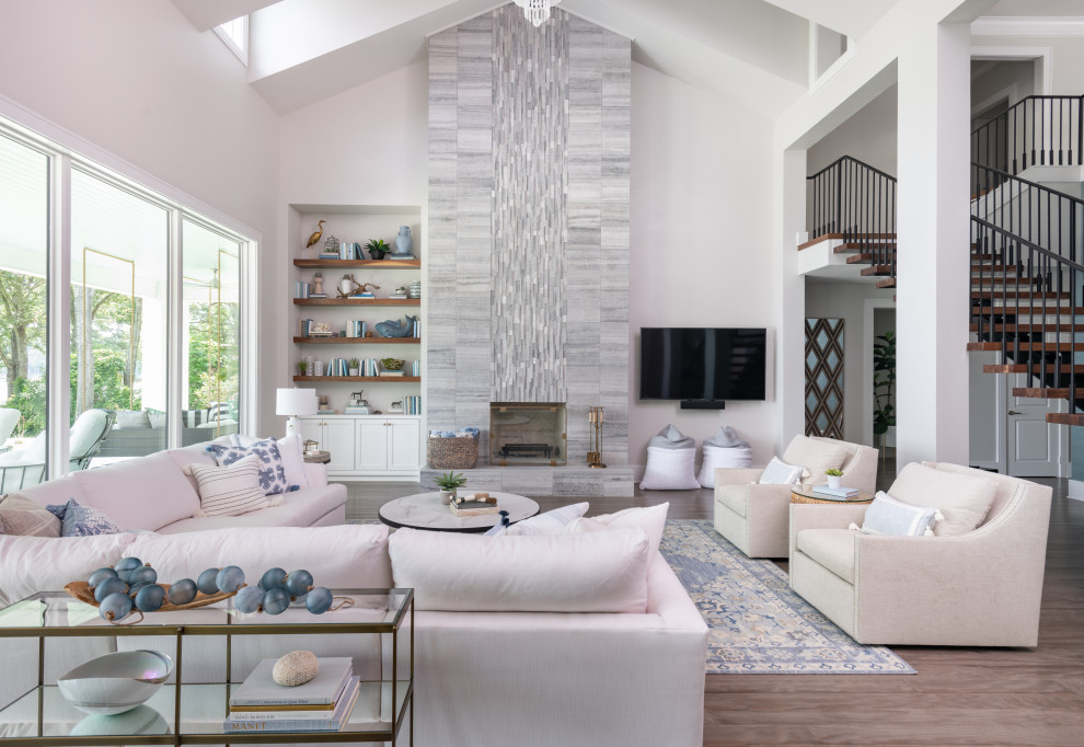 This is an example of a large beach style open concept family room in Dallas with grey walls, porcelain floors, a standard fireplace, a stone fireplace surround, a wall-mounted tv, brown floor and vaulted.