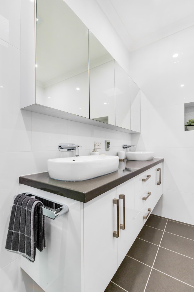 Large modern master wet room bathroom in Adelaide with shaker cabinets, white cabinets, a freestanding tub, a two-piece toilet, white tile, ceramic tile, white walls, ceramic floors, a vessel sink, granite benchtops, brown floor, a hinged shower door and brown benchtops.