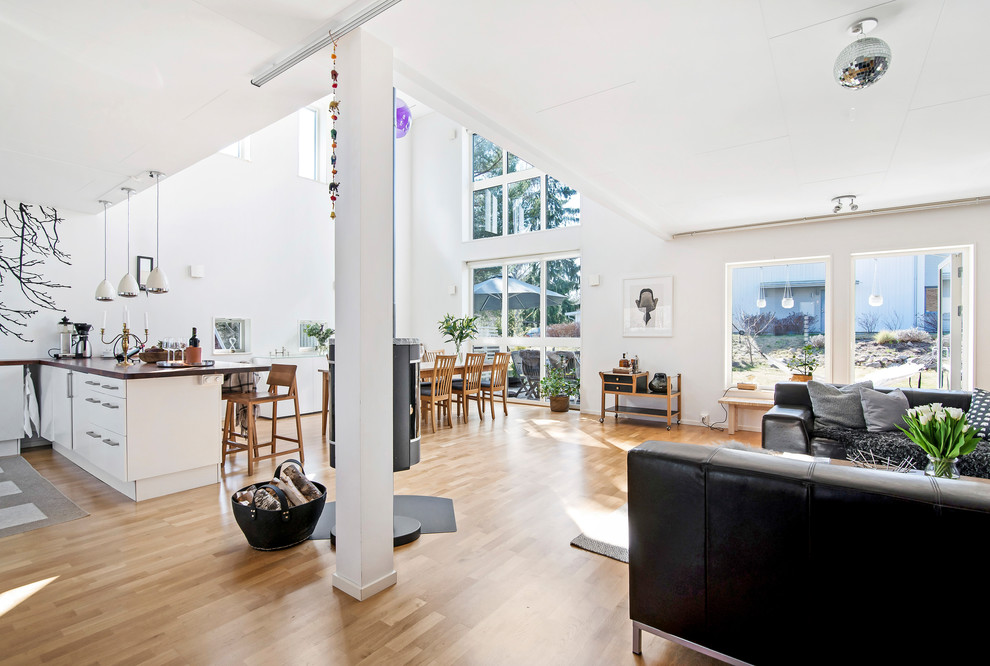 This is an example of a large contemporary open concept living room in Stockholm with white walls, light hardwood floors, no fireplace and brown floor.