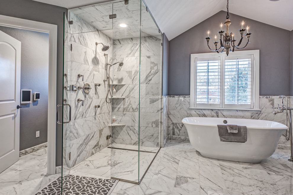 Photo of a large transitional master bathroom in Denver with a freestanding tub, a curbless shower, white tile, stone tile, grey walls and marble floors.