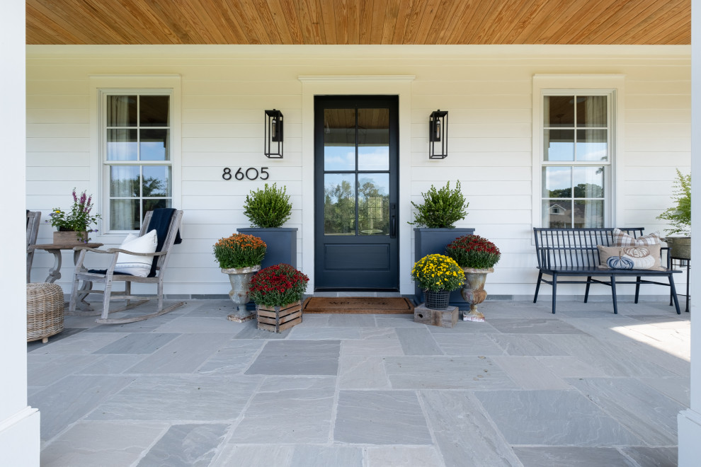 Inspiration for an expansive traditional front veranda in Little Rock with with columns, natural stone paving and an awning.