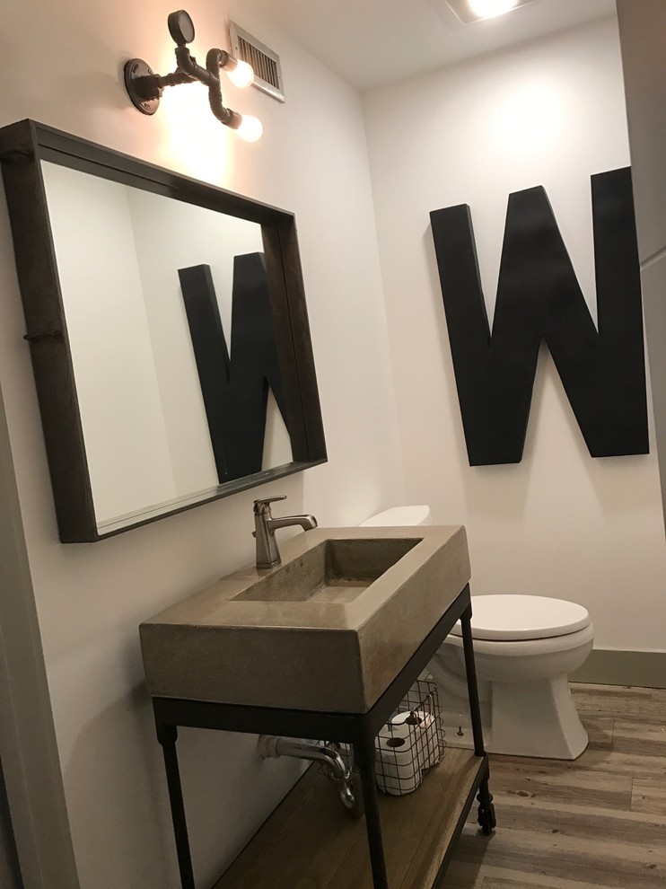 This is an example of a mid-sized industrial 3/4 bathroom in Austin with open cabinets, a two-piece toilet, white walls, dark hardwood floors, an integrated sink, concrete benchtops and brown floor.