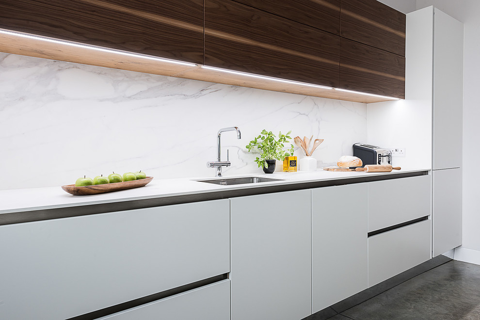Contemporary kitchen in London with an undermount sink, flat-panel cabinets, white cabinets, white splashback and stone slab splashback.