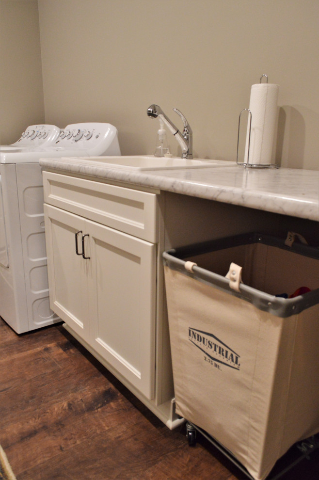 Inspiration for a mid-sized traditional galley dedicated laundry room in Chicago with a drop-in sink, shaker cabinets, white cabinets, laminate benchtops, beige walls, medium hardwood floors, a side-by-side washer and dryer, brown floor and grey benchtop.