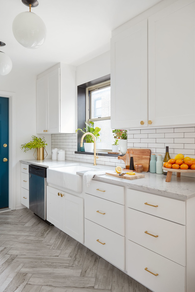 Mid-sized transitional galley separate kitchen in Chicago with a farmhouse sink, white cabinets, white splashback, stainless steel appliances, no island, flat-panel cabinets, marble benchtops, porcelain splashback, travertine floors and grey floor.