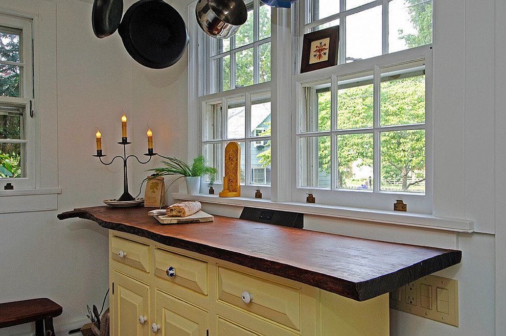 Design ideas for a small eclectic u-shaped separate kitchen in Philadelphia with a farmhouse sink, raised-panel cabinets, yellow cabinets, terra-cotta splashback, white appliances, slate floors, no island, wood benchtops and beige splashback.