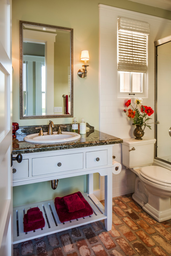 Inspiration for a small arts and crafts bathroom in Santa Barbara with a one-piece toilet, green walls, brick floors, open cabinets, white cabinets, an alcove tub, a shower/bathtub combo, white tile, ceramic tile, a drop-in sink and granite benchtops.