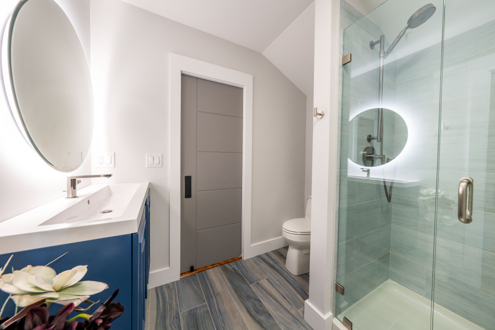 Modern inredning av ett mellanstort vit vitt badrum med dusch, med möbel-liknande, blå skåp, en dusch i en alkov, en toalettstol med hel cisternkåpa, beige väggar, klinkergolv i keramik, bänkskiva i täljsten, blått golv och dusch med gångjärnsdörr