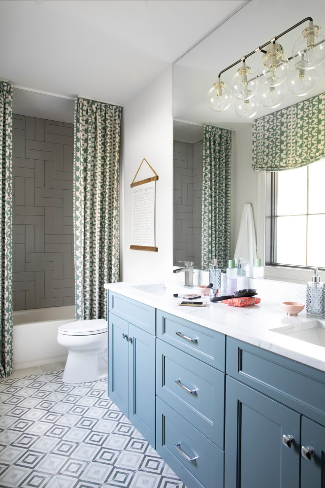 This is an example of a mid-sized country 3/4 bathroom in Atlanta with recessed-panel cabinets, blue cabinets, an alcove tub, a shower/bathtub combo, a two-piece toilet, white walls, cement tiles, an undermount sink, quartzite benchtops, multi-coloured floor, a shower curtain and white benchtops.