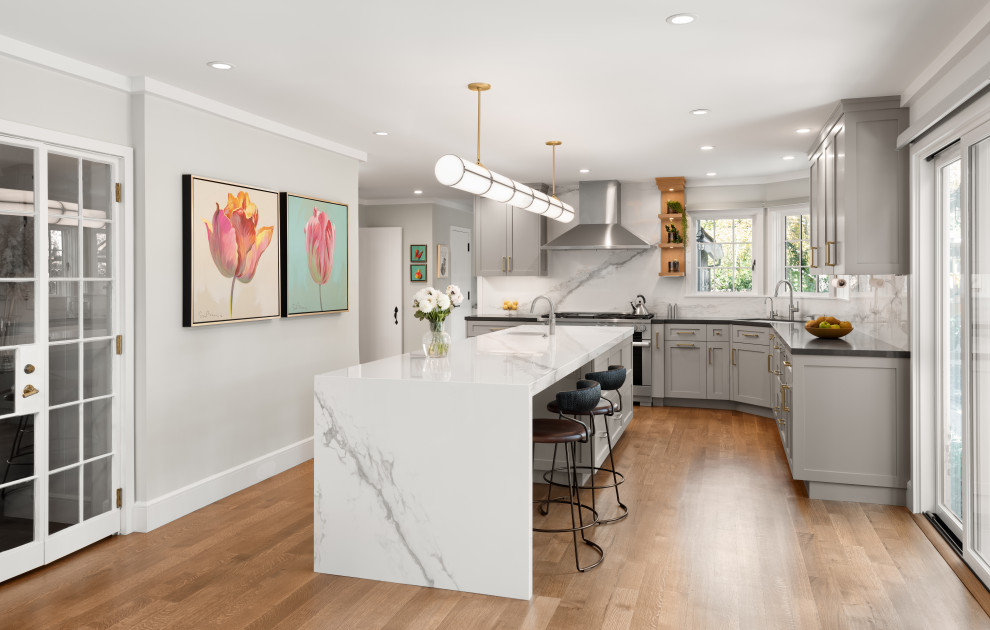 Large transitional l-shaped kitchen in San Francisco with an undermount sink, shaker cabinets, quartzite benchtops, white splashback, granite splashback, stainless steel appliances, with island, black benchtop, grey cabinets, medium hardwood floors and brown floor.