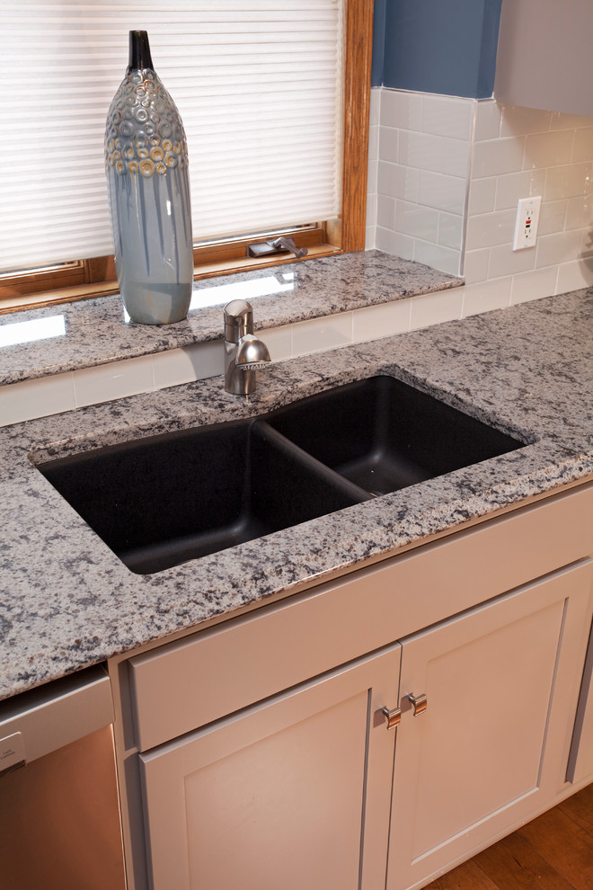 This is an example of a mid-sized transitional l-shaped separate kitchen in Minneapolis with an undermount sink, recessed-panel cabinets, grey cabinets, quartz benchtops, white splashback, porcelain splashback, stainless steel appliances, medium hardwood floors and with island.