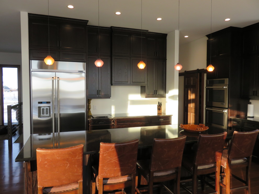 Large transitional l-shaped dark wood floor open concept kitchen photo with recessed-panel cabinets, dark wood cabinets, quartz countertops, stainless steel appliances, an island and an undermount sink