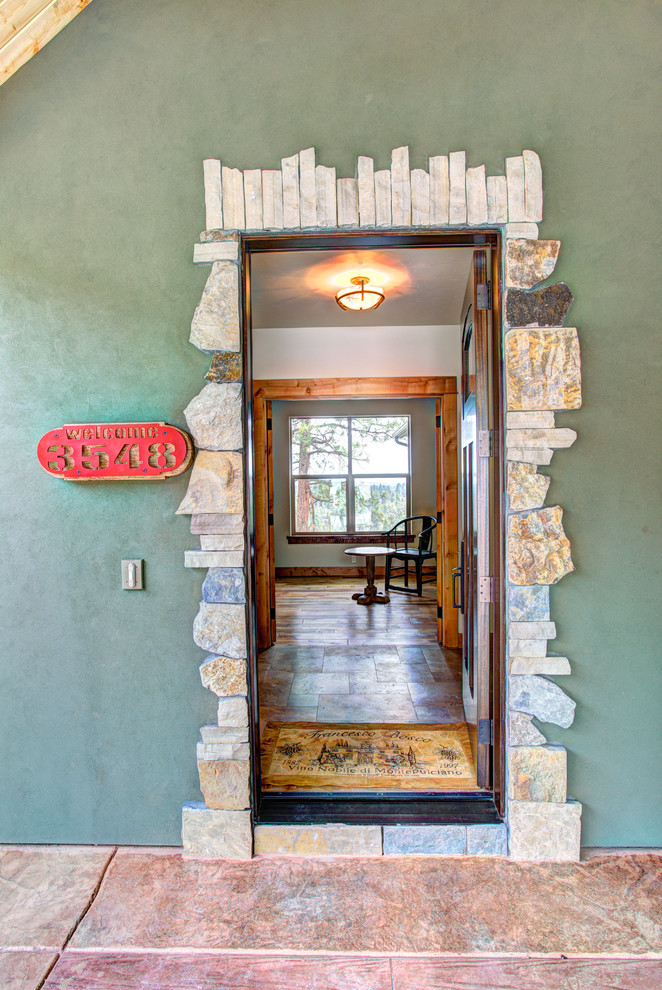 Example of a large mountain style front door design with green walls and a dark wood front door