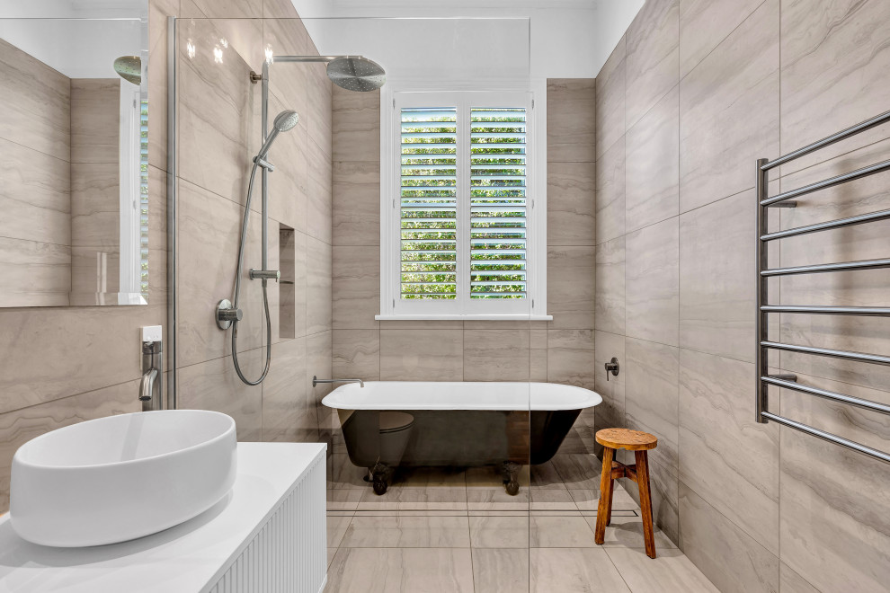 Klassisk inredning av ett stort vit vitt en-suite badrum, med luckor med profilerade fronter, vita skåp, ett badkar med tassar, en öppen dusch, beige kakel, stenkakel, beige väggar, klinkergolv i porslin, ett fristående handfat, granitbänkskiva, beiget golv och med dusch som är öppen