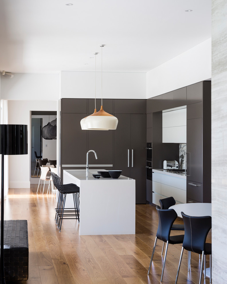 Photo of a contemporary galley eat-in kitchen in Adelaide with flat-panel cabinets, grey splashback, panelled appliances, medium hardwood floors, with island and brown floor.