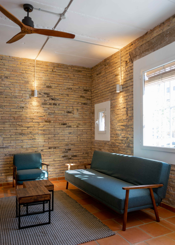 Diseño de sala de estar abierta mediterránea de tamaño medio con paredes marrones, suelo de baldosas de terracota, televisor colgado en la pared, suelo marrón y ladrillo