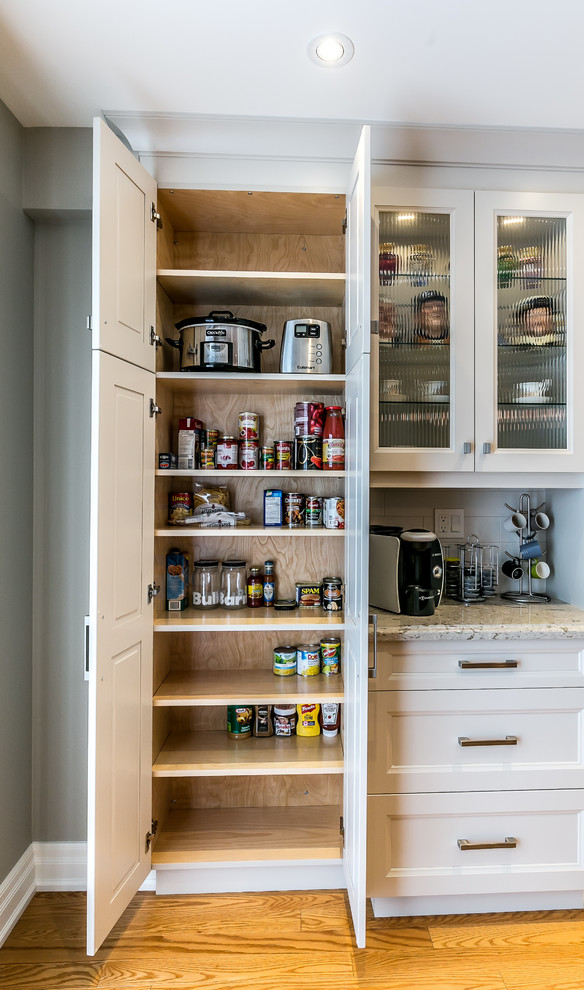 Mid-sized transitional l-shaped brown floor kitchen photo in Toronto with a double-bowl sink, white cabinets, white backsplash, stainless steel appliances and an island