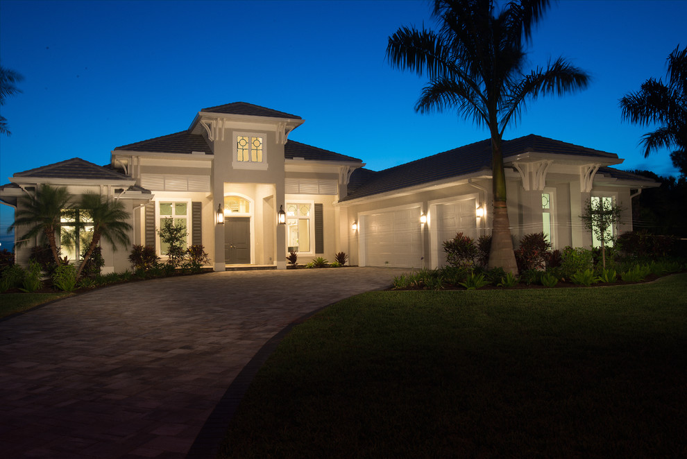 This is an example of a mid-sized tropical one-storey stucco beige house exterior in Orlando with a hip roof and a tile roof.