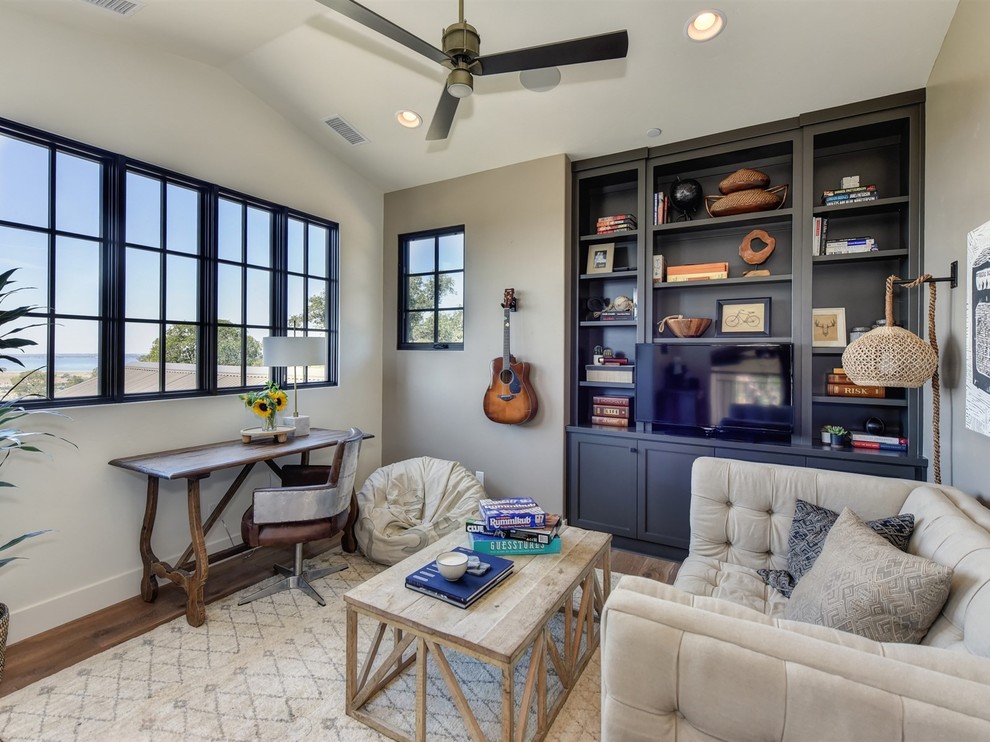 Example of a transitional medium tone wood floor family room library design in Sacramento with beige walls, no fireplace and a media wall