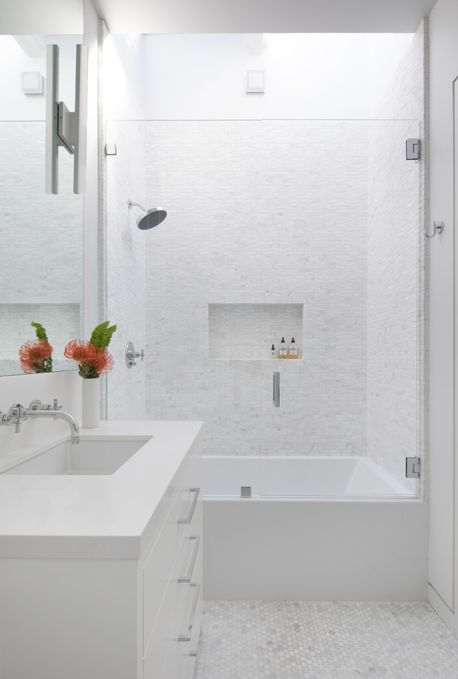 Photo of a mid-sized contemporary kids bathroom in San Francisco with flat-panel cabinets, white cabinets, an alcove tub, white tile, marble, marble floors, engineered quartz benchtops, white floor, a hinged shower door and white benchtops.