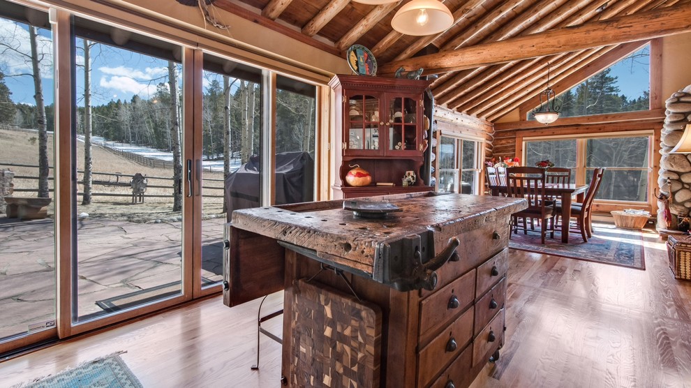 Mountain style l-shaped medium tone wood floor kitchen photo in Denver with a farmhouse sink, raised-panel cabinets, distressed cabinets, granite countertops and an island