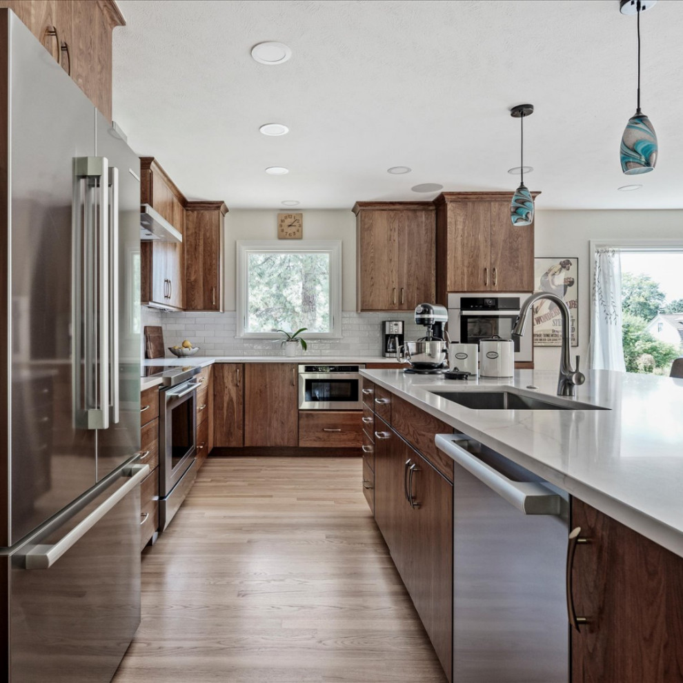 Inspiration for a large transitional l-shaped light wood floor and brown floor eat-in kitchen remodel in Denver with an undermount sink, flat-panel cabinets, medium tone wood cabinets, quartzite countertops, white backsplash, ceramic backsplash, stainless steel appliances, an island and white countertops