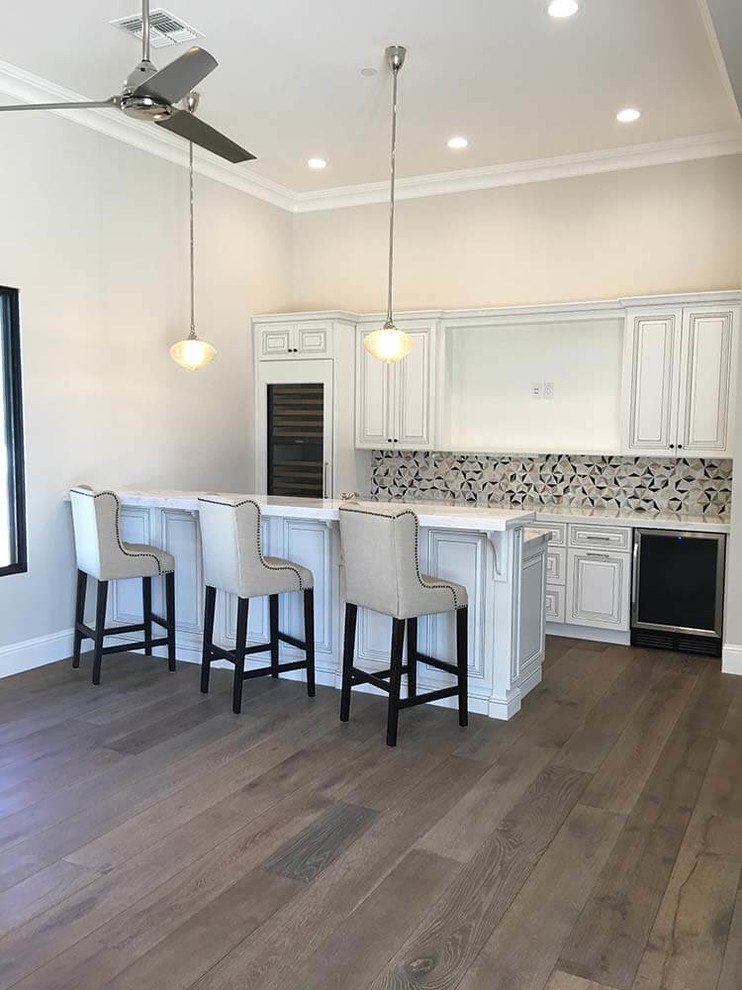 This is an example of a large modern single-wall wet bar in Phoenix with recessed-panel cabinets, yellow cabinets, quartzite benchtops, dark hardwood floors, brown floor and grey benchtop.