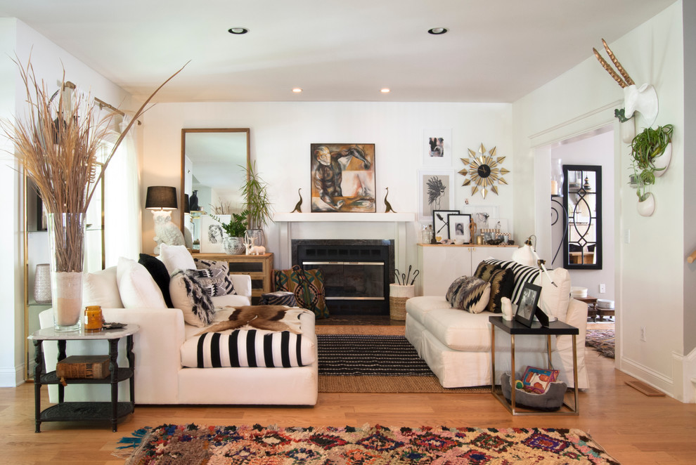 Photo of a mid-sized eclectic formal open concept living room in Cleveland with white walls, medium hardwood floors, a standard fireplace and no tv.