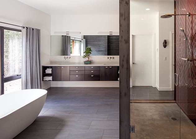 Large modern master bathroom in Portland with flat-panel cabinets, dark wood cabinets, a freestanding tub, an open shower, a two-piece toilet, white walls, vinyl floors, a wall-mount sink, solid surface benchtops, brown floor, a hinged shower door and white benchtops.