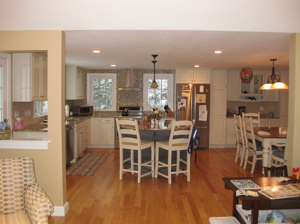Transitional l-shaped light wood floor eat-in kitchen photo in Boston with an island, an undermount sink, raised-panel cabinets, white cabinets, granite countertops, beige backsplash, ceramic backsplash and stainless steel appliances