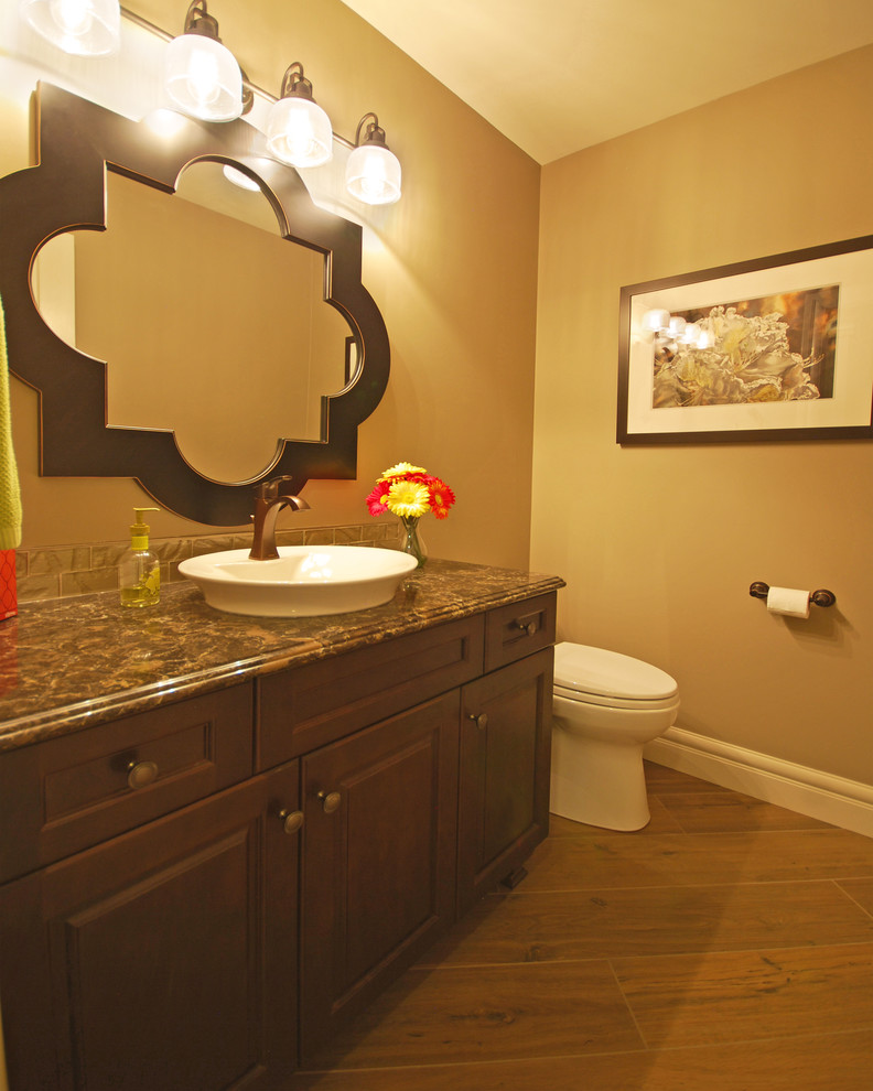 This is an example of a small transitional powder room in Edmonton with a vessel sink, raised-panel cabinets, dark wood cabinets, engineered quartz benchtops, a one-piece toilet, beige tile and grey walls.