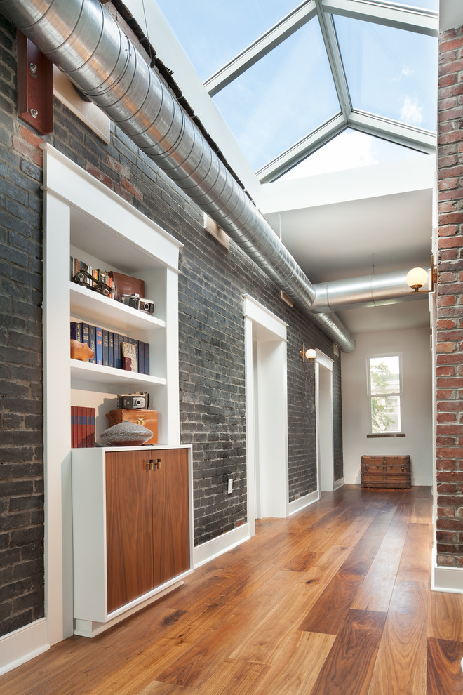 Design ideas for a mid-sized industrial hallway in DC Metro with black walls and medium hardwood floors.