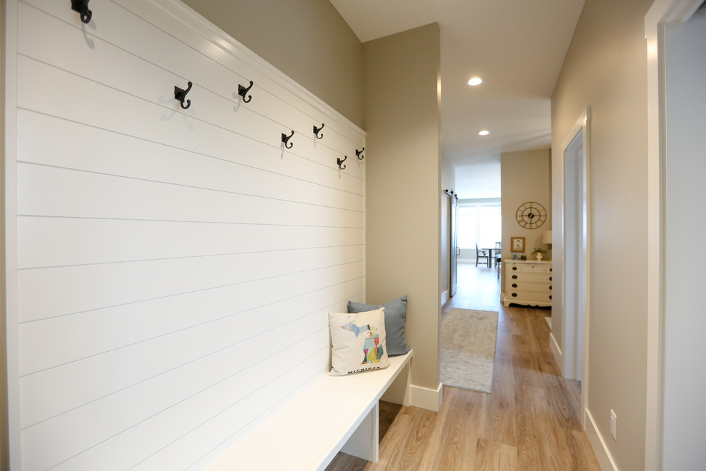 Example of a mid-sized transitional light wood floor and brown floor mudroom design with beige walls and a gray front door