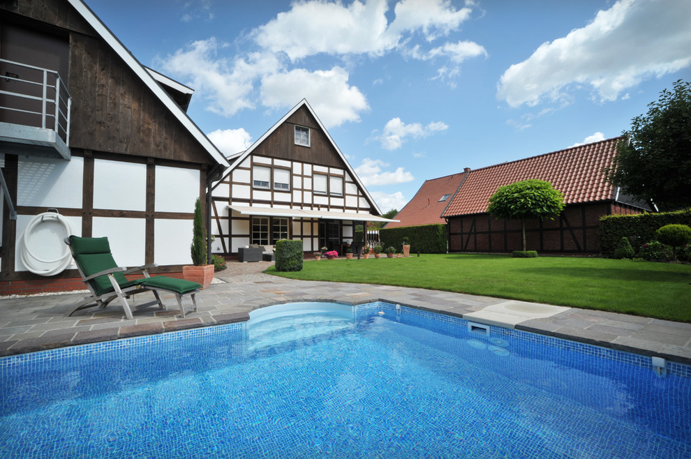 Mittelgroßer Moderner Pool hinter dem Haus in rechteckiger Form mit Natursteinplatten in Sonstige