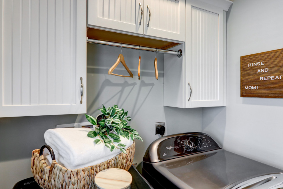 This is an example of a small traditional single-wall separated utility room in Other with louvered cabinets, white cabinets, grey walls, ceramic flooring, a side by side washer and dryer and beige floors.