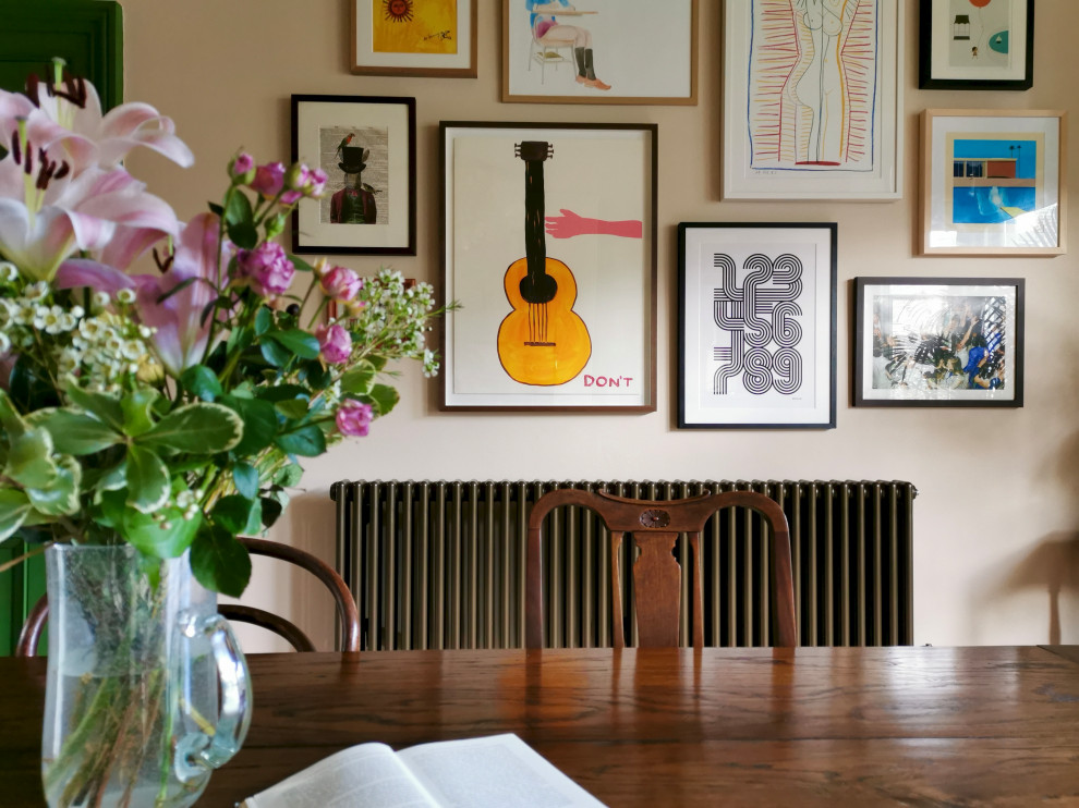 Idée de décoration pour une salle à manger ouverte sur la cuisine tradition de taille moyenne avec un mur rose, un sol en bois brun, une cheminée standard, un manteau de cheminée en pierre et un sol marron.