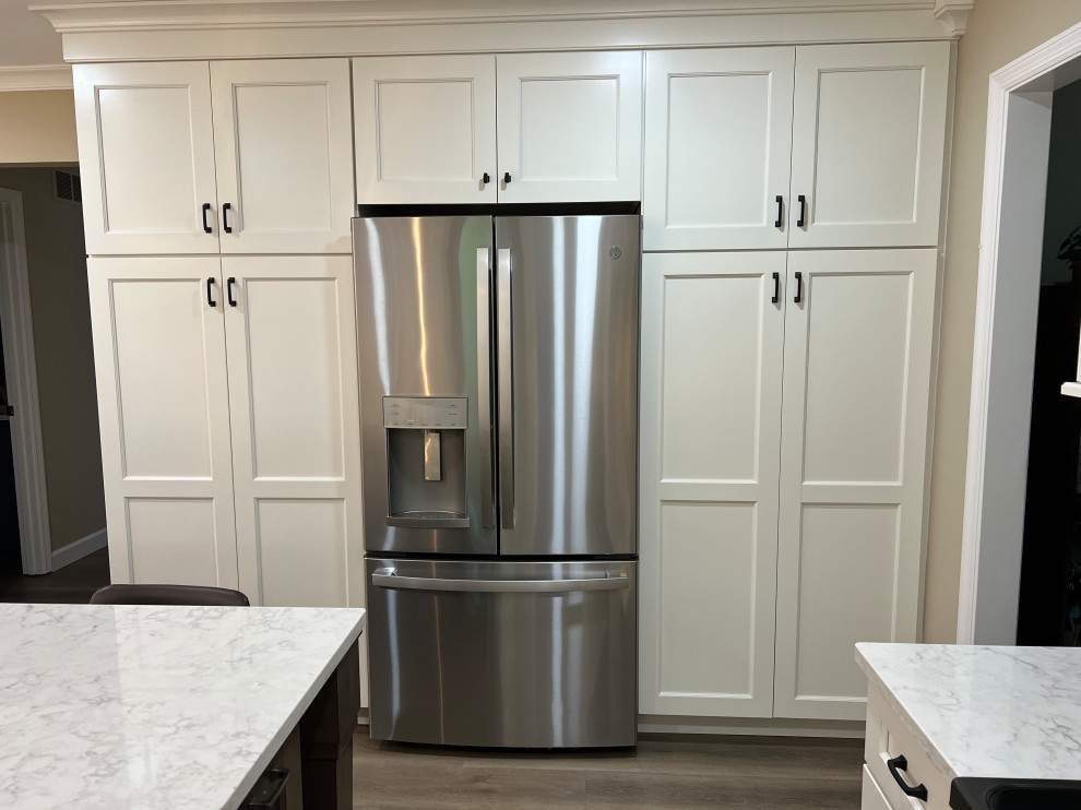 Kitchen pantry - mid-sized transitional l-shaped laminate floor and brown floor kitchen pantry idea in Cincinnati with an undermount sink, recessed-panel cabinets, white cabinets, quartz countertops, gray backsplash, stone tile backsplash, stainless steel appliances, an island and white countertops