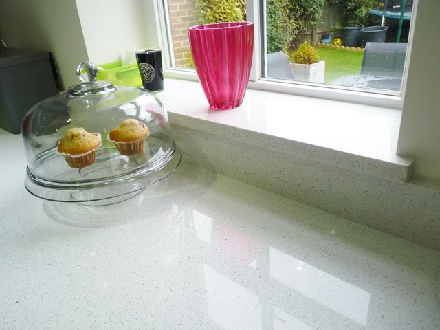 Gloss lacquered 'graphite' handleless kitchen with white quartz worktops contemporaneo-cocina