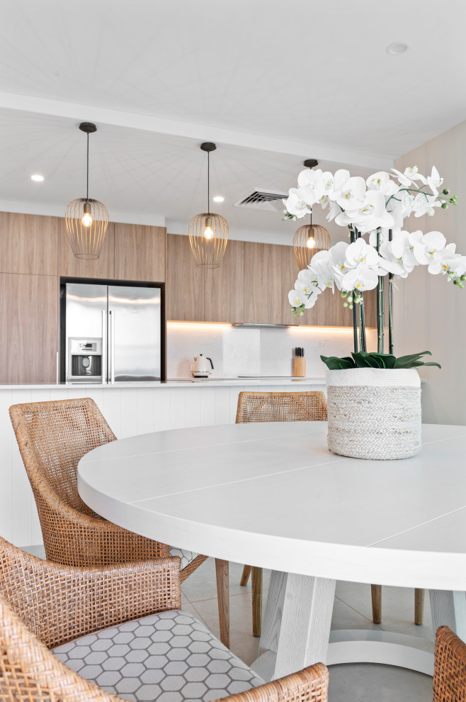 This is an example of a beach style galley eat-in kitchen in Gold Coast - Tweed with medium wood cabinets, solid surface benchtops, stone slab splashback, stainless steel appliances, porcelain floors and white benchtop.