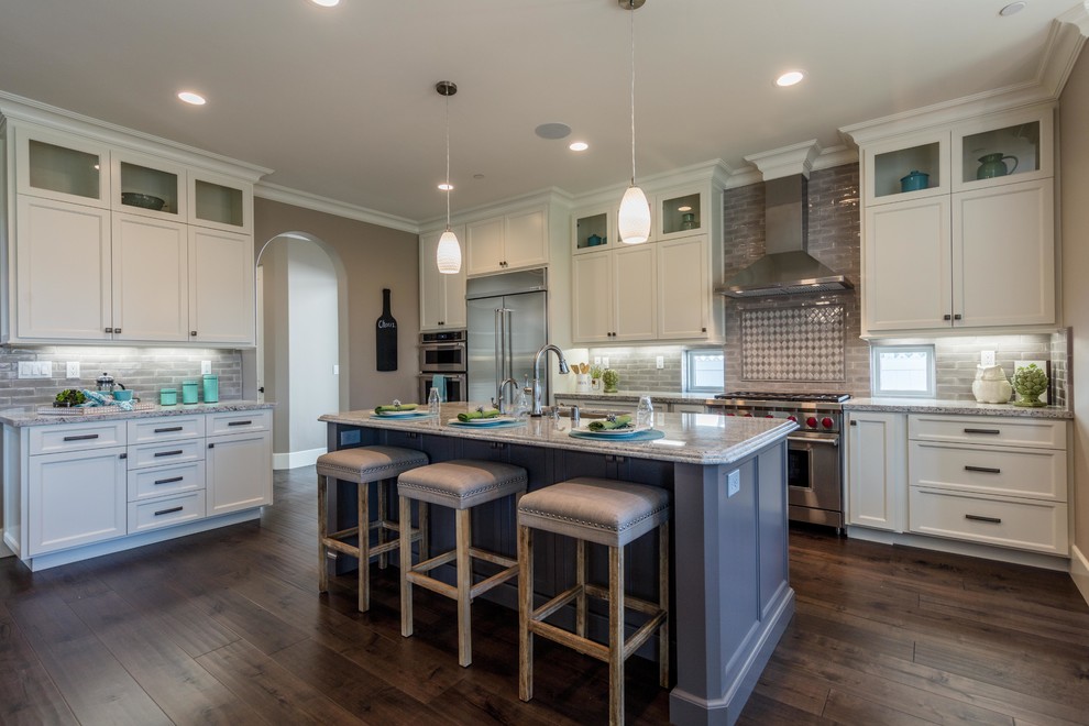 Example of a mid-sized transitional u-shaped medium tone wood floor and brown floor eat-in kitchen design in San Francisco with an undermount sink, shaker cabinets, white cabinets, granite countertops, gray backsplash, subway tile backsplash, stainless steel appliances, an island and gray countertops