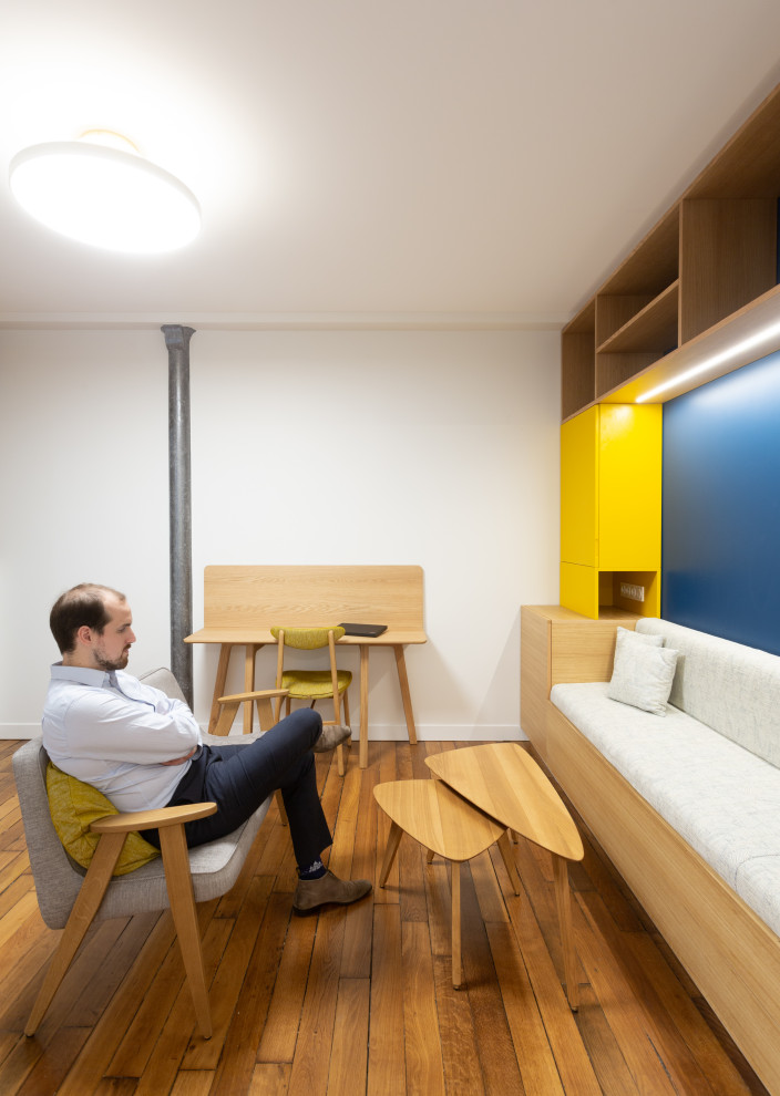 Diseño de sala de estar abierta contemporánea pequeña con paredes azules y suelo de madera en tonos medios