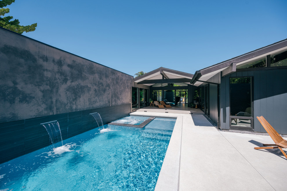 Mittelgroßer Mid-Century Pool in rechteckiger Form mit Wasserspiel und Betonplatten in Orange County